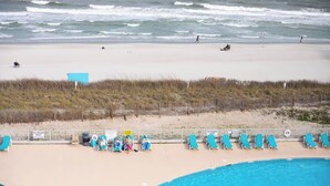 Una playa con piscina, sillas de playa y un puesto de salvavidas.