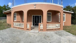 A single-story building with a curved facade, a central door, and a small porch with a balustrade. - Double Luxury Queen Apt#3 in Roseau with Kitchenette and Gorgeous Bathroom!  (Roseau)