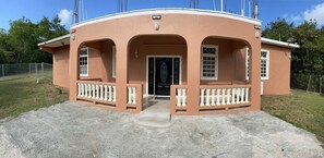 A single-story building with a curved facade, a central door, and a small porch with a balustrade. - Double Luxury Queen Apt#3 in Roseau with Kitchenette and Gorgeous Bathroom!  (Roseau)