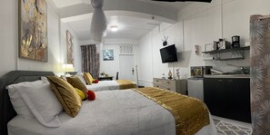 Een hotelkamer met twee bedden, een televisie, een bureau en een koffiezetapparaat.