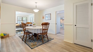 A dining area with a round table, four wooden chairs, a patterned rug, and a ceiling light.