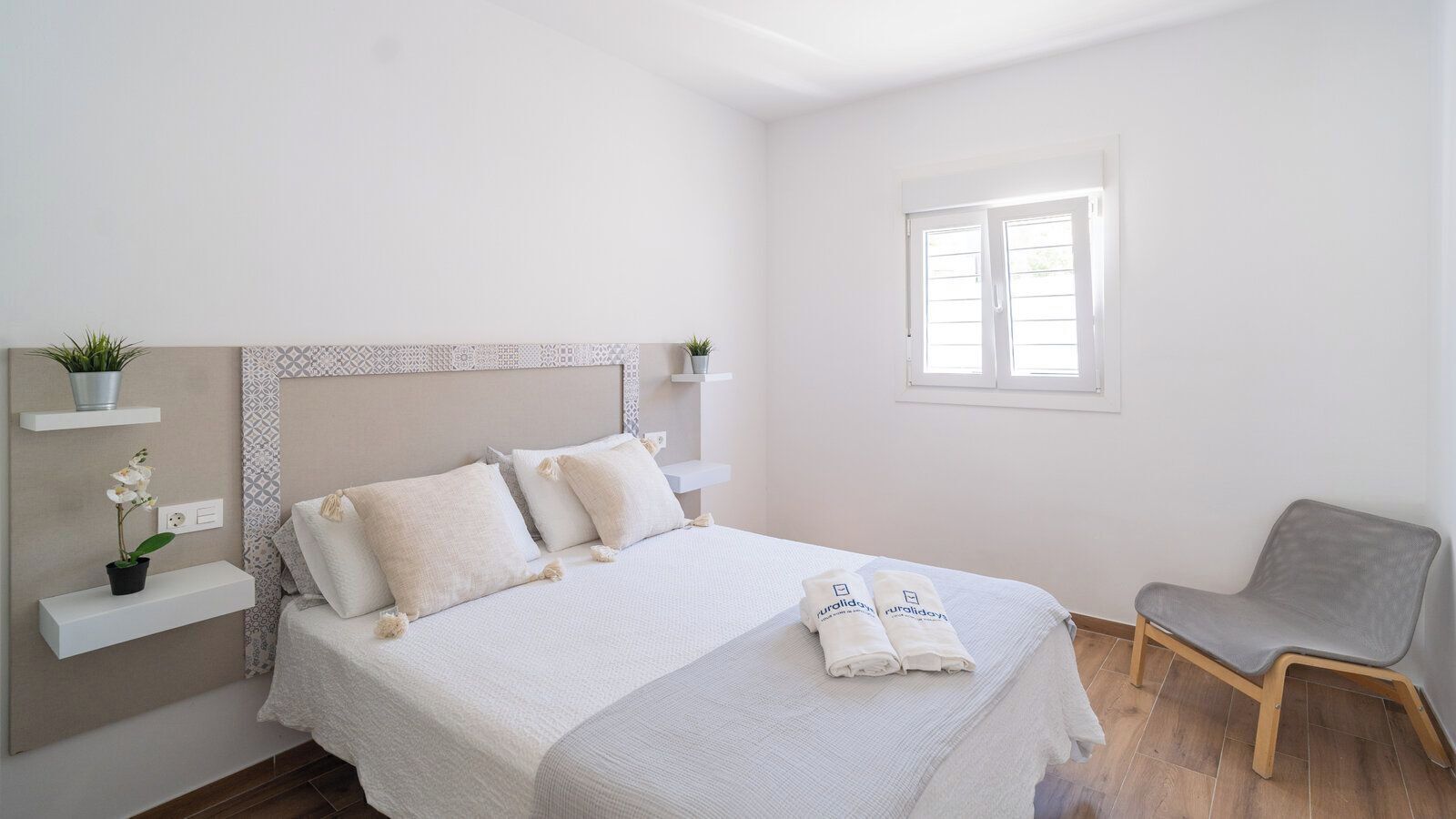 A bedroom with a bed, a chair, and a window.