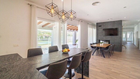 Un espace repas moderne avec une longue table, des chaises et un saladier rempli de fruits.
