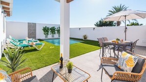 Une terrasse avec une piscine, du mobilier d’extérieur et une table sur laquelle se trouvent une bouteille et un verre.