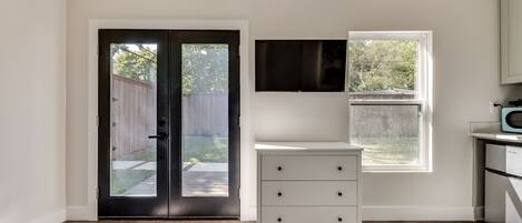 A room with a black door, a white cabinet, and a window overlooking a backyard.