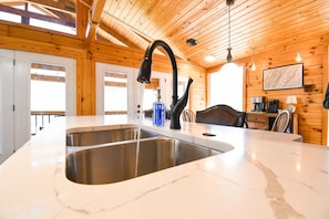 Experience a warm and inviting kitchen with a large sink, curved faucet, and high ceiling.