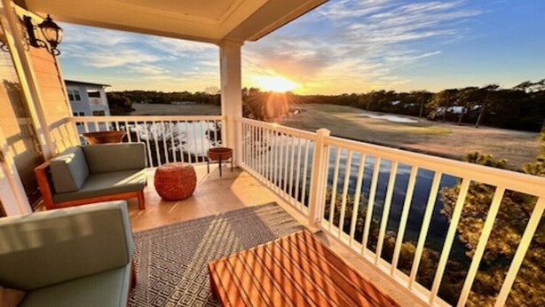 A covered balcony with a sofa, a wooden table, and a rug. - St James Golf Resort-Luxe 3/3 Condo, Sleeps8, Pool, 1DogOk, Gated (St. James Bay)