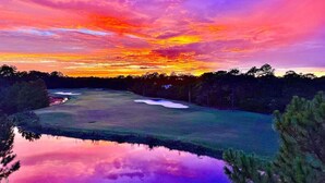A golf course with a water body reflecting the sky, surrounded by trees. - St James Golf Resort-Luxe 3/3 Condo, Sleeps8, Pool, 1DogOk, Gated (St. James Bay)