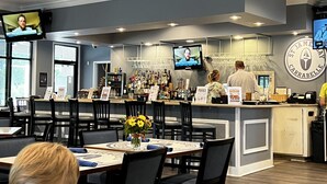 A restaurant with a bar area, multiple TVs, and a logo on the wall. - St James Golf Resort-Luxe 3/3 Condo, Sleeps8, Pool, 1DogOk, Gated (St. James Bay)