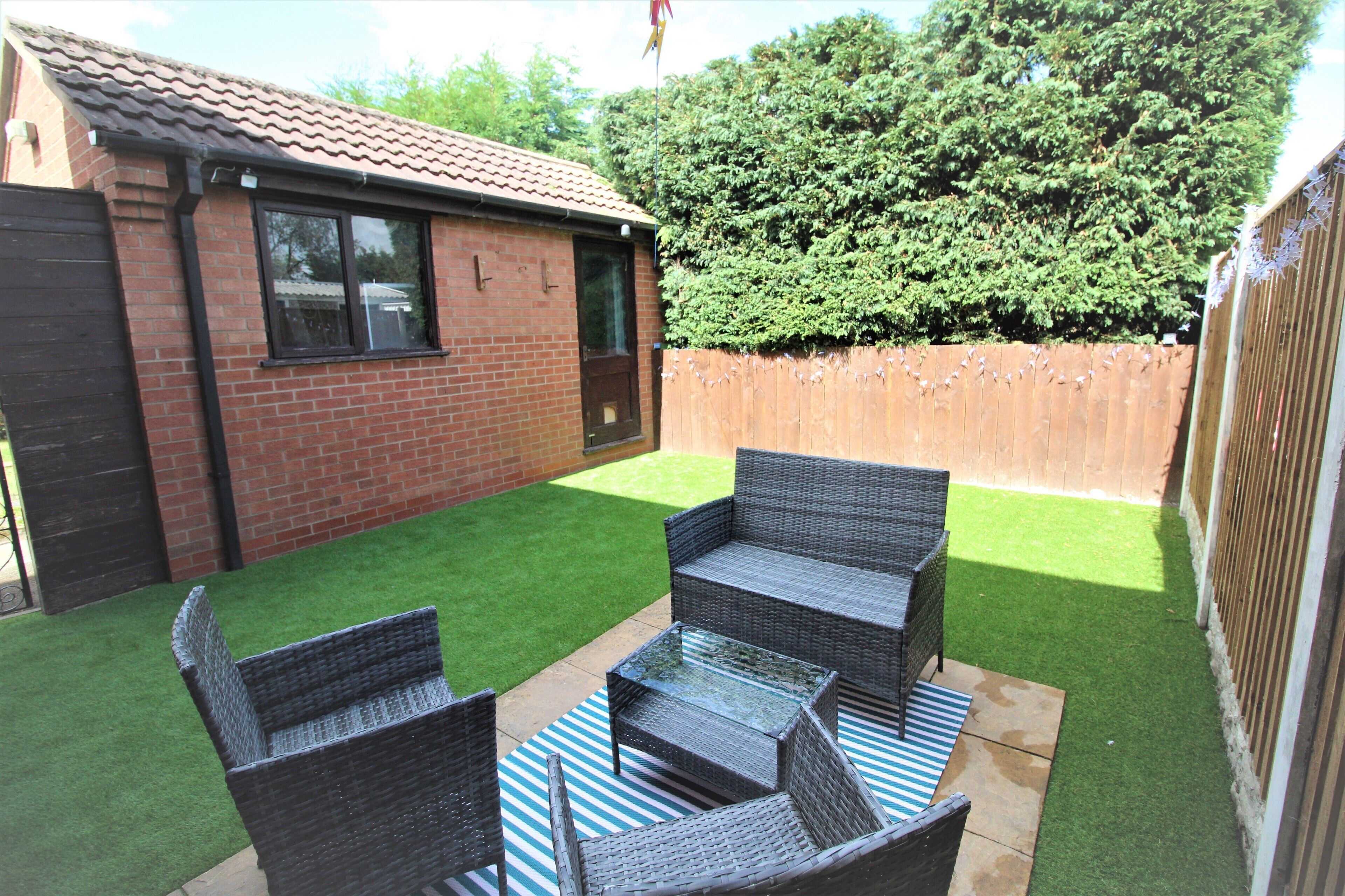 A patio with wicker furniture and artificial grass.