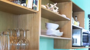 Uma cozinha com prateleiras de madeira que exibem livros, copos e utensílios de cozinha.