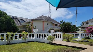 A residential area with houses, a white fence, and a garden. - Cozyville in the Manor (Ocho Rios)