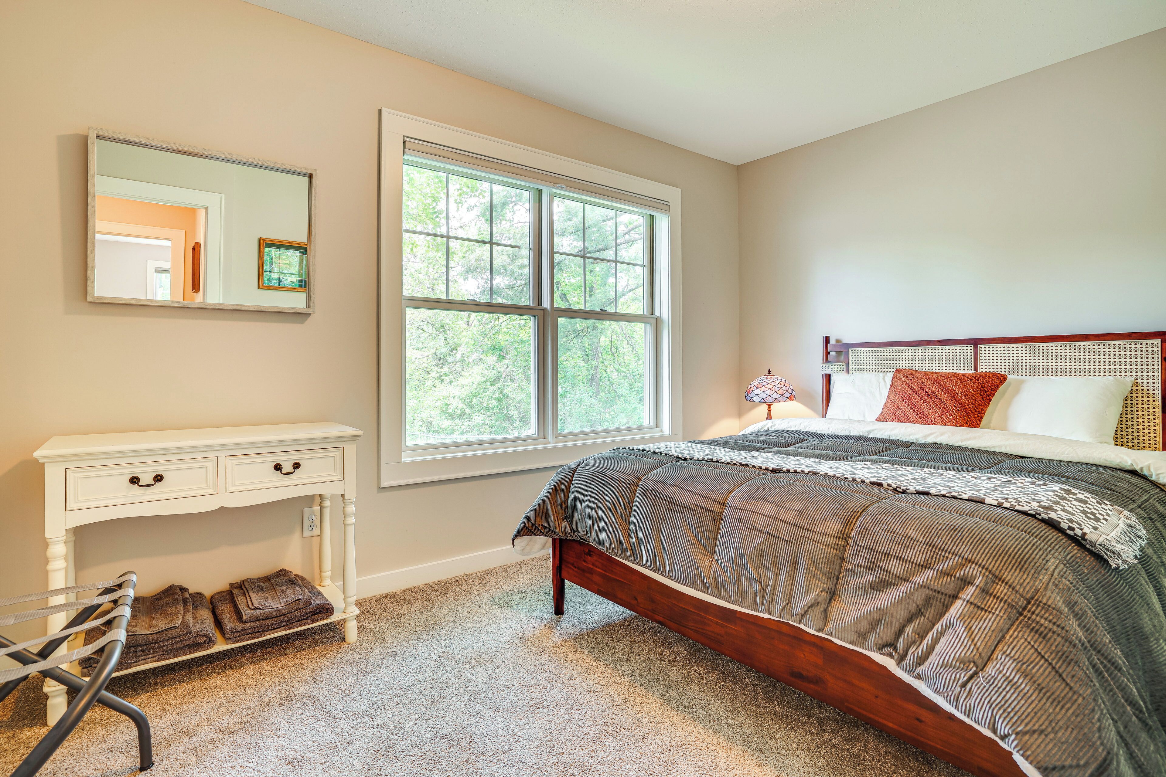 Une chambre à coucher avec un lit, une commode, un miroir et une fenêtre.