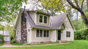 A two-story house with a stone chimney, a front porch, and a well-maintained lawn.