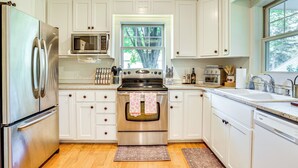 A modern kitchen with white cabinetry, stainless steel appliances, a microwave, oven, and a dishwasher.