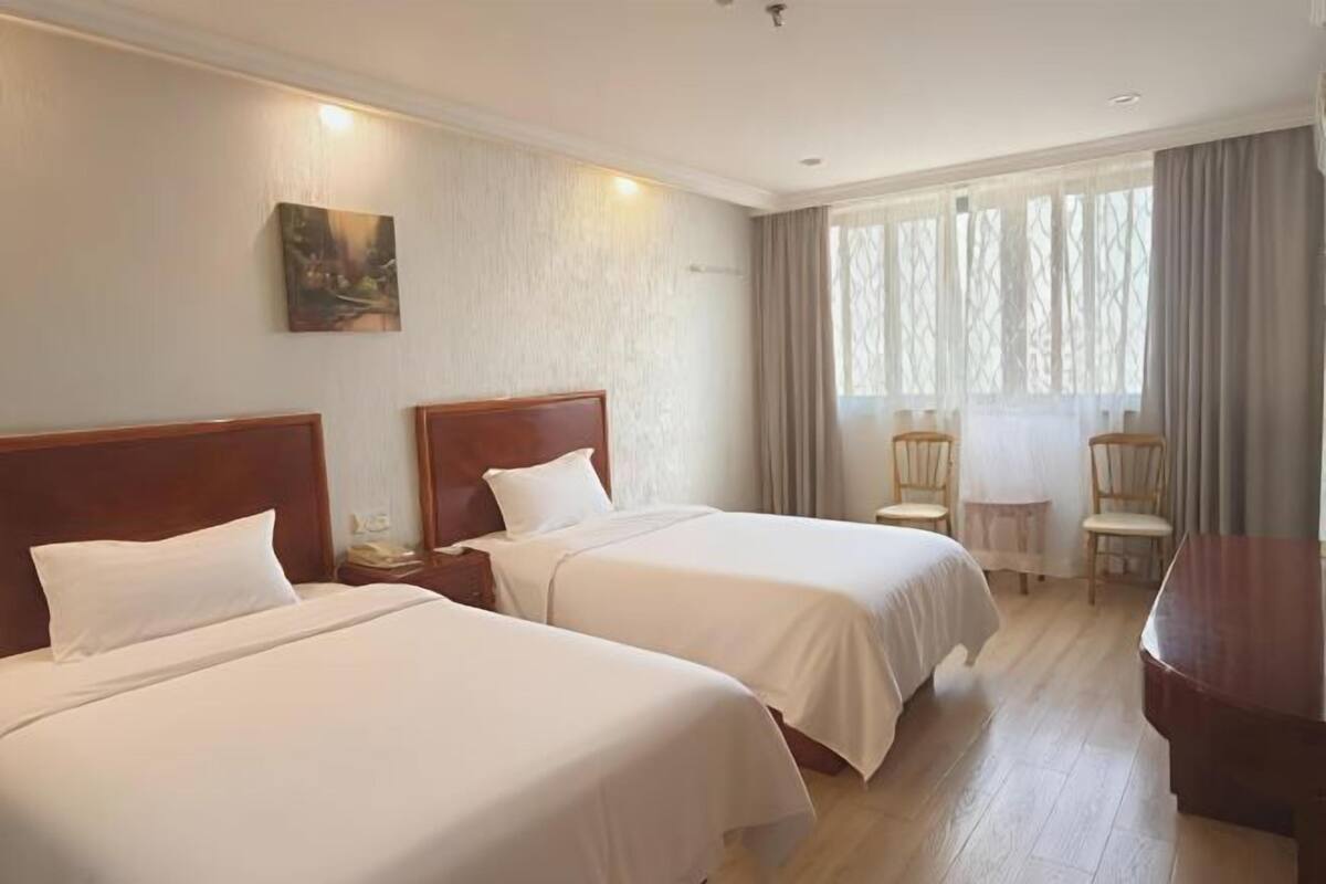 A hotel room with two beds, a desk, and a chair.