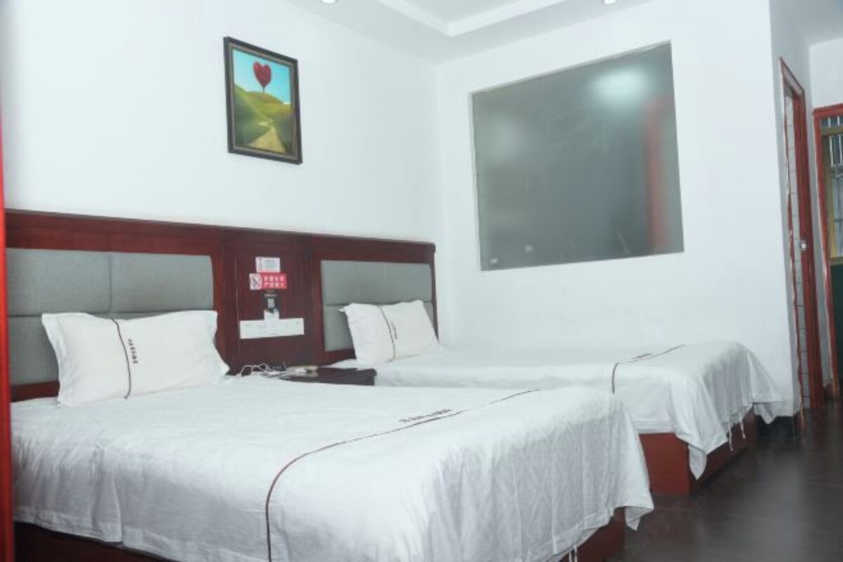 A hotel room with two beds, a large window, and a framed picture on the wall.