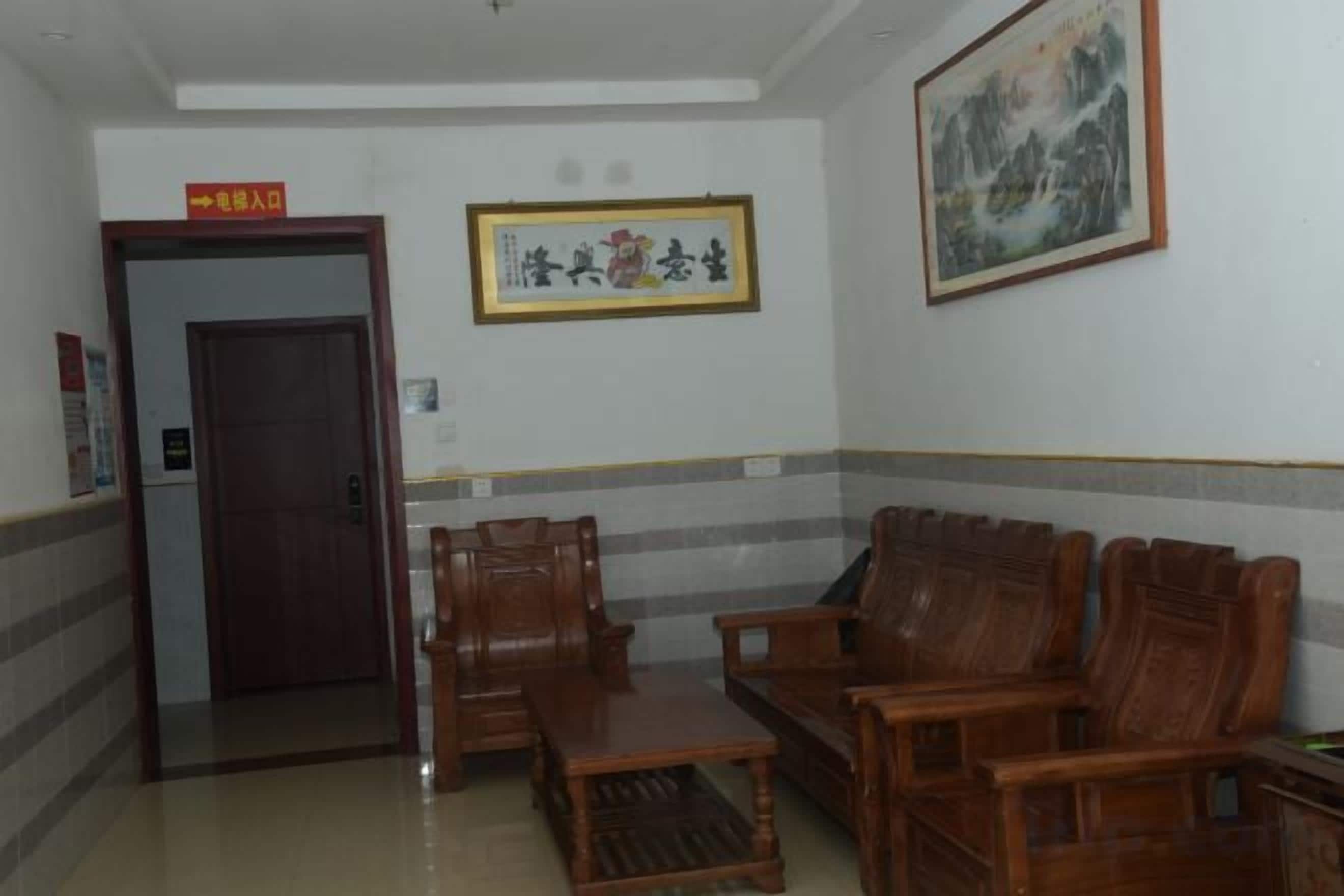 A lobby with a reception desk, wooden chairs, a sofa, and a framed artwork on the wall.
