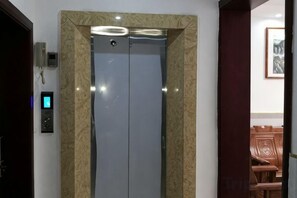 An elevator with a control panel and a wall-mounted intercom. - Huachen Business Hotel (Wan'an)