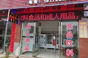 A storefront with glass doors, signs indicating food and beverage services, and a red awning. - Huachen Business Hotel (Wan'an)
