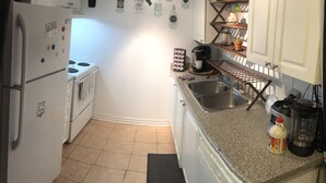 A compact kitchen with white cabinets, a refrigerator, a stove, a coffee maker, and a sink. - Nice clean apartment 5 minutes from subway (Toronto)