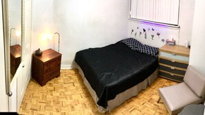 A bedroom with a bed, a dresser, a nightstand, a mirror, and a wall-mounted shelf with decorative items. - Nice clean apartment 5 minutes from subway (Toronto)