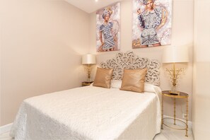 A bedroom with a large bed, ornate headboard, two bedside tables with lamps, and decorative pillows.