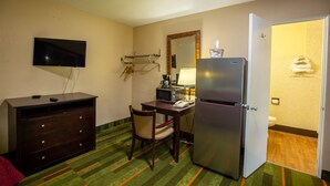 A hotel room with a flat-screen TV, a desk with a microwave, a refrigerator, a chair, and a bed with a red blanket. - Budget Host Inn (Gilman)