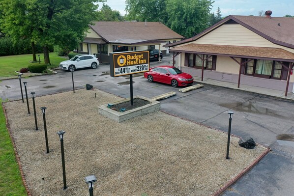 A Budget Host Inn with a clear driveway, a parking area, and a well-maintained lawn.