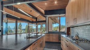 Une cuisine moderne avec des meubles en bois, un grand îlot central et une vue sur l’extérieur.