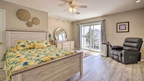 Ein Schlafzimmer mit einem Bett, einem Deckenventilator, einem Sessel, einem Fenster und einer Tür.
