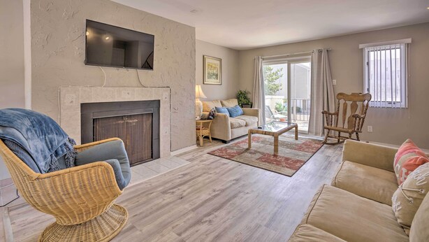 Ein Wohnzimmer mit Kamin, Korbsesseln, einer Couch und einem an der Wand befestigten Fernseher.
