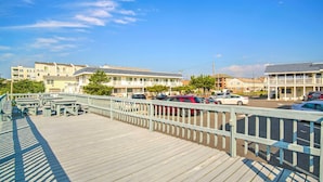 A wooden boardwalk with picnic tables and a parking area with cars.