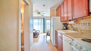 A kitchen with wooden cabinets, a refrigerator, a stove, and a ceiling fan.