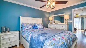A bedroom with a bed, nightstands, a dresser, a ceiling fan, and a mirror.