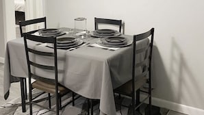Ruokailutilassa on neljälle katettu pöytä, jonka ympärillä on tuoleja. Pöydän yläpuolella olevalla seinällä on kolme taulua.