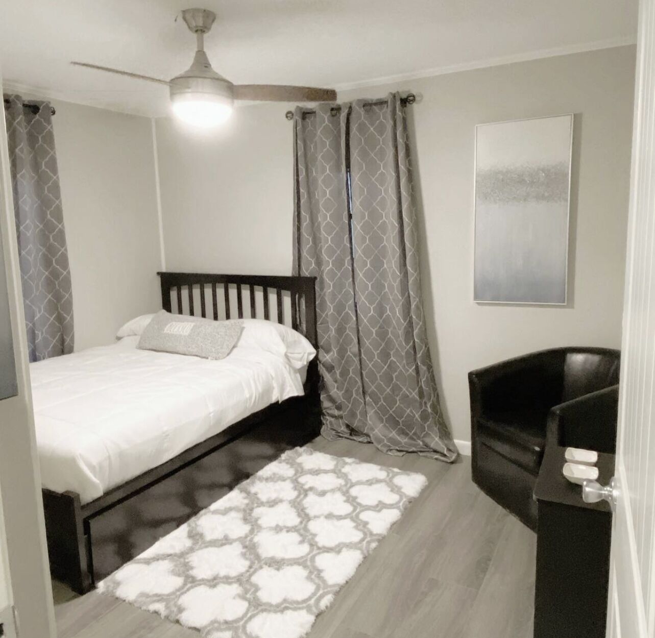 A bedroom with a bed, a ceiling fan, a chair, and a rug.