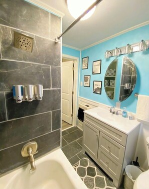 A bathroom with a bathtub, a sink, a mirror, and a shower.