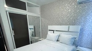 Quarto com cama, guarda-roupa, mesa de cabeceira e ar condicionado.