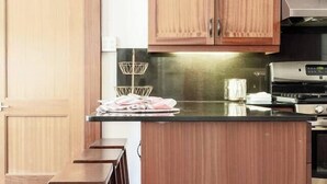 Una cucina con mobili in legno, un fornello in acciaio inossidabile e un piano di lavoro nero.