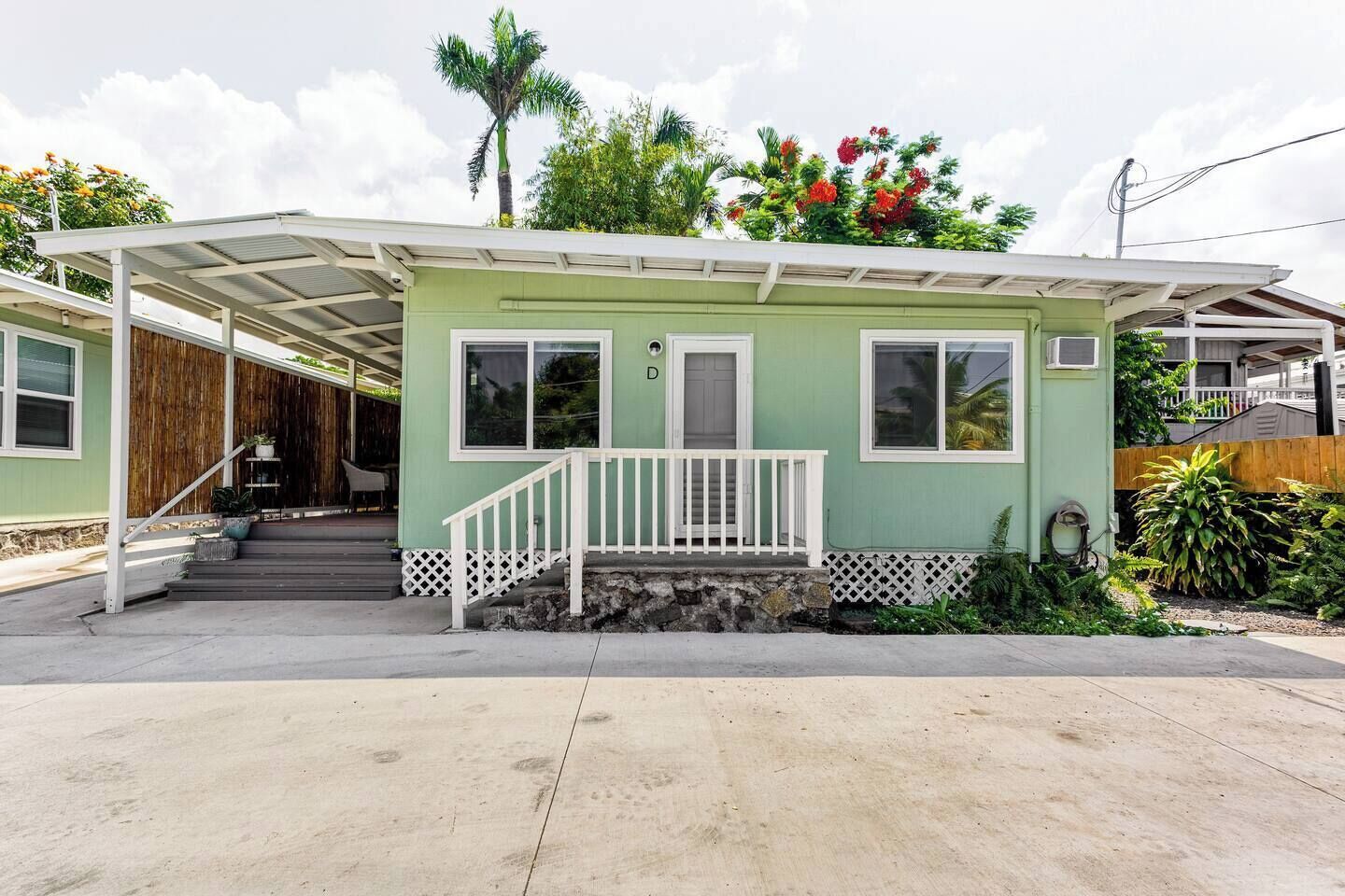 A single-story house with a covered porch, a small front yard with plants, and a clear sky.