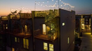 A multi-story building with balconies, string lights, and a tree on the side.