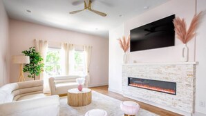 A modern living room with a fireplace, a sofa, a coffee table, and a TV mounted on the wall.