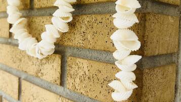 A white lei with shells hanging on a brick wall.