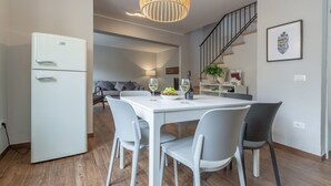 A modern kitchen with a white refrigerator, a dining table with chairs, and a hanging light fixture. - Lovely apartment for 6 people with WIFI, A/C and TV (Fano)