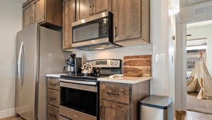 A kitchen with wooden cabinets, stainless steel appliances, and a modern design. - Moose Meadows Escape in McCall - dog friendly & 1 bed/1 bath on each of 3 floors (McCall)