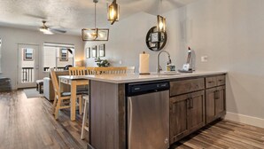 A modern kitchen with a central island, wooden cabinets, and pendant lighting. - Moose Meadows Escape in McCall - dog friendly & 1 bed/1 bath on each of 3 floors (McCall)