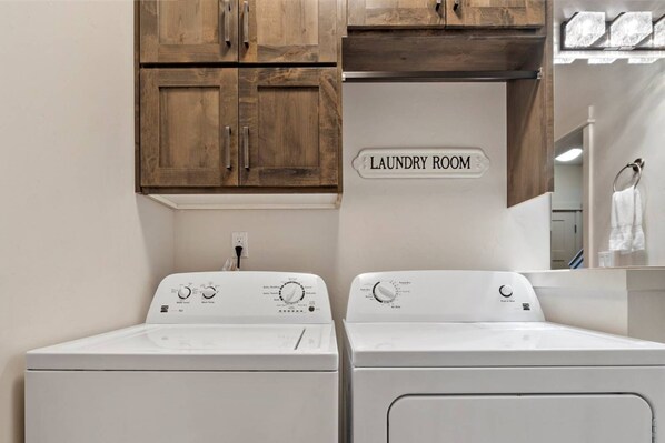 A laundry room with two front-loading washers and a wooden cabinet above. - Moose Meadows Escape in McCall - dog friendly & 1 bed/1 bath on each of 3 floors (McCall)