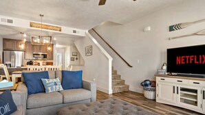 A living room with a grey sofa, a television, and a wooden ceiling fan. - Moose Meadows Escape in McCall - dog friendly & 1 bed/1 bath on each of 3 floors (McCall)