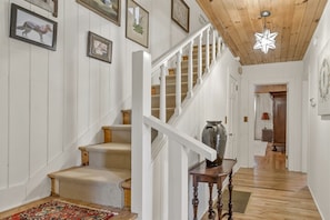 Staircase and artwork adorn this inviting space, featuring a large vase and patterned rug.
